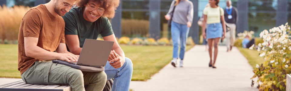 University students outdoors on campus, discussing and working together, illustrating the importance of CMS for higher education institutions.