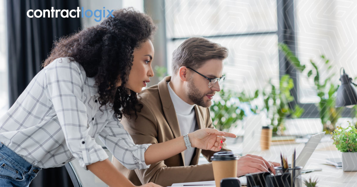 business woman pointing at laptop computer with colleague in office using contract lifecycle management software