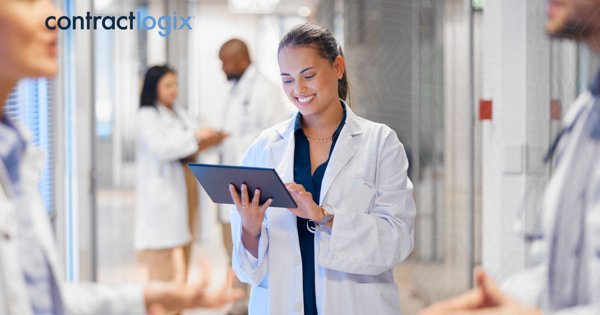 healthcare professionals speak while a woman in a lab coat uses contract management software for healthcare on a tablet