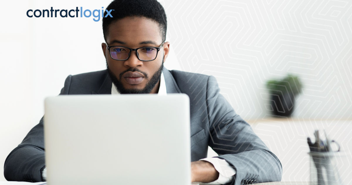 An administrator sits at desk in office with computer and uses CLM software for school districts