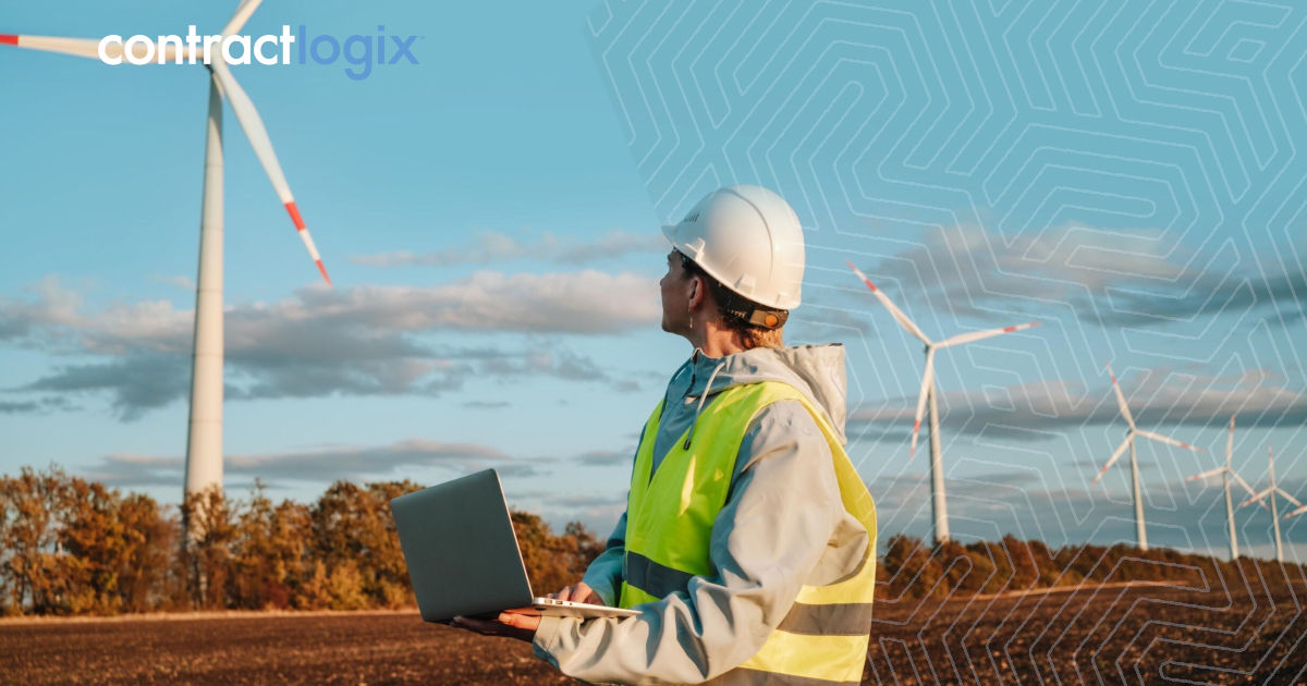 Woman holds a laptop to navigate contract management software for energy as she looks toward wind turbines