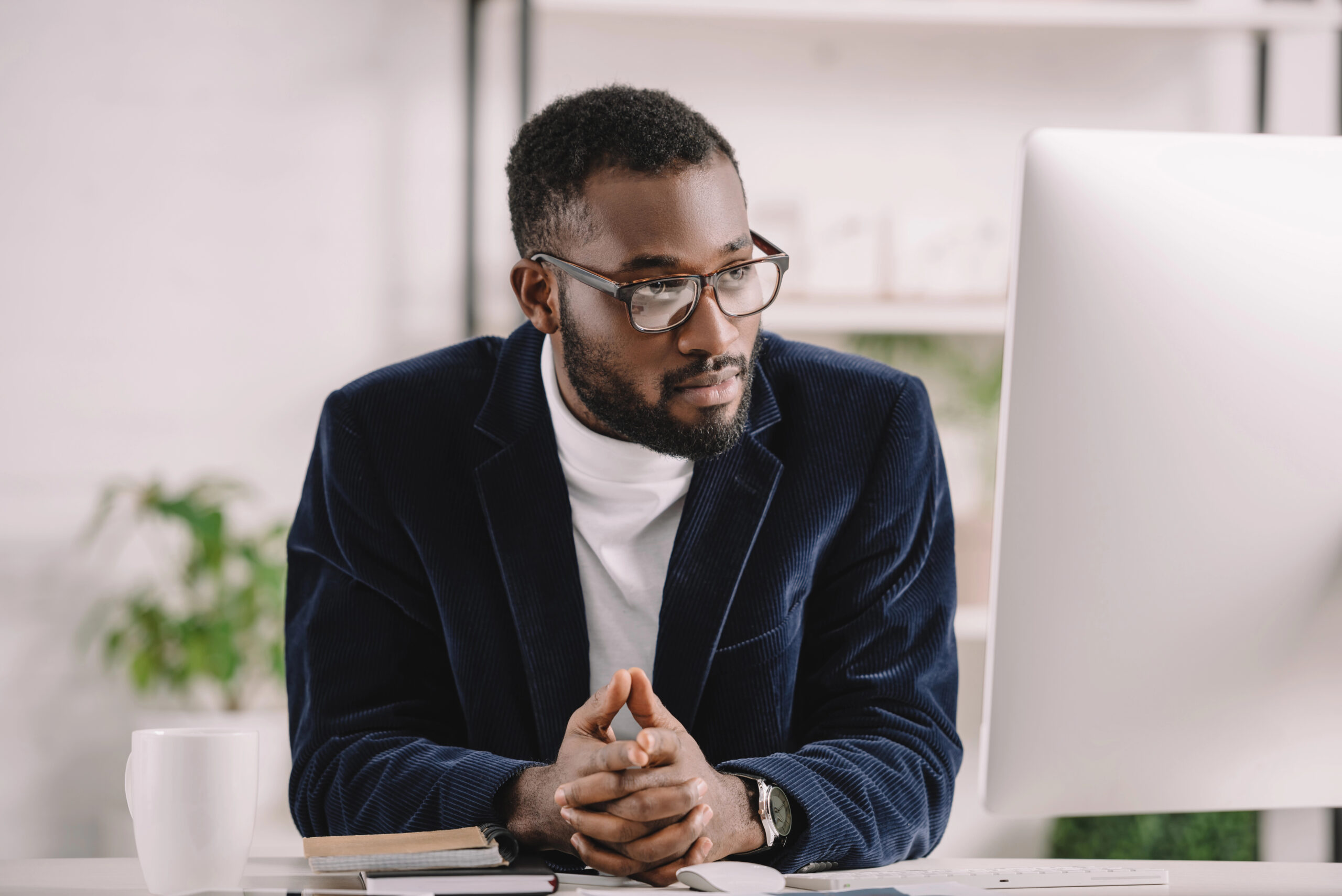 businessman sits at desk and looks at computer screen after learning about contract management software