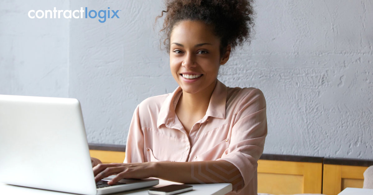 smiling woman uses laptop computer after learning what is contract lifecycle management software