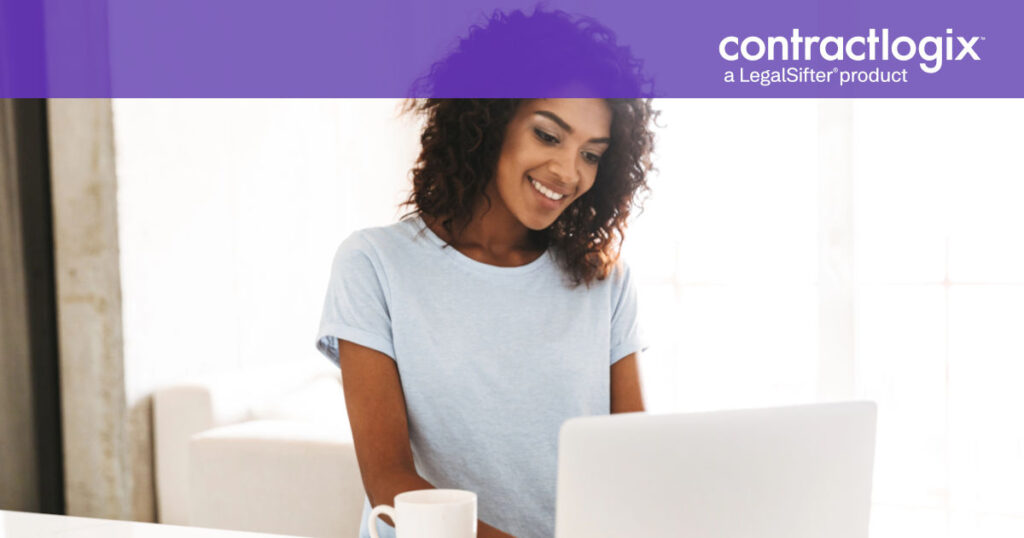 smiling woman sits at desk and uses computer to learn about the best contract database software