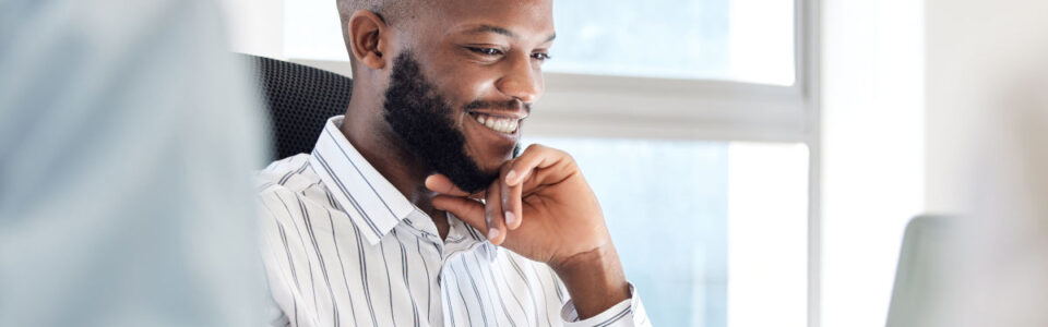 happy man sits in office on laptop computer after learning how Contract Management Supports Business Continuity