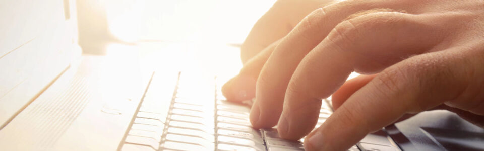Man’s hands typing on laptop keyboard to learn about contract management software for mid-market