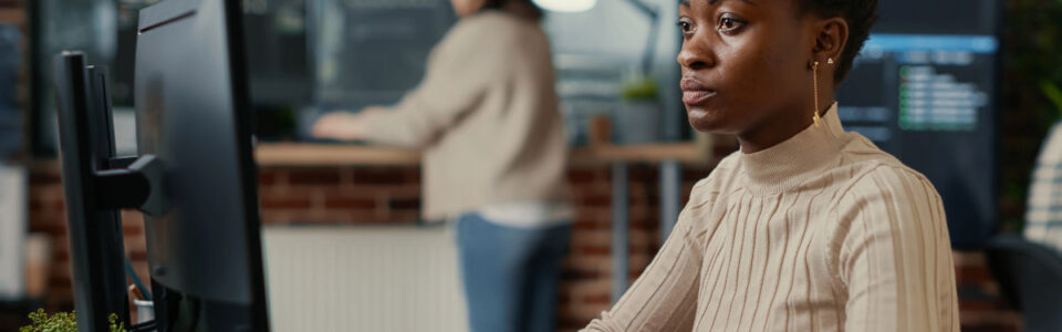 female businesswoman sits at desktop computer and learns about contract management consulting services
